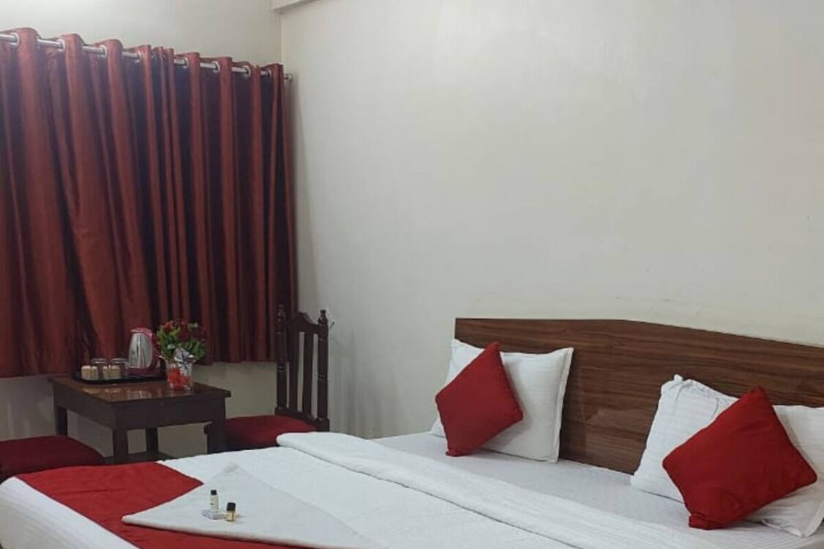 A neatly made bed with a wooden headboard, a red and white bedspread, and matching pillows.