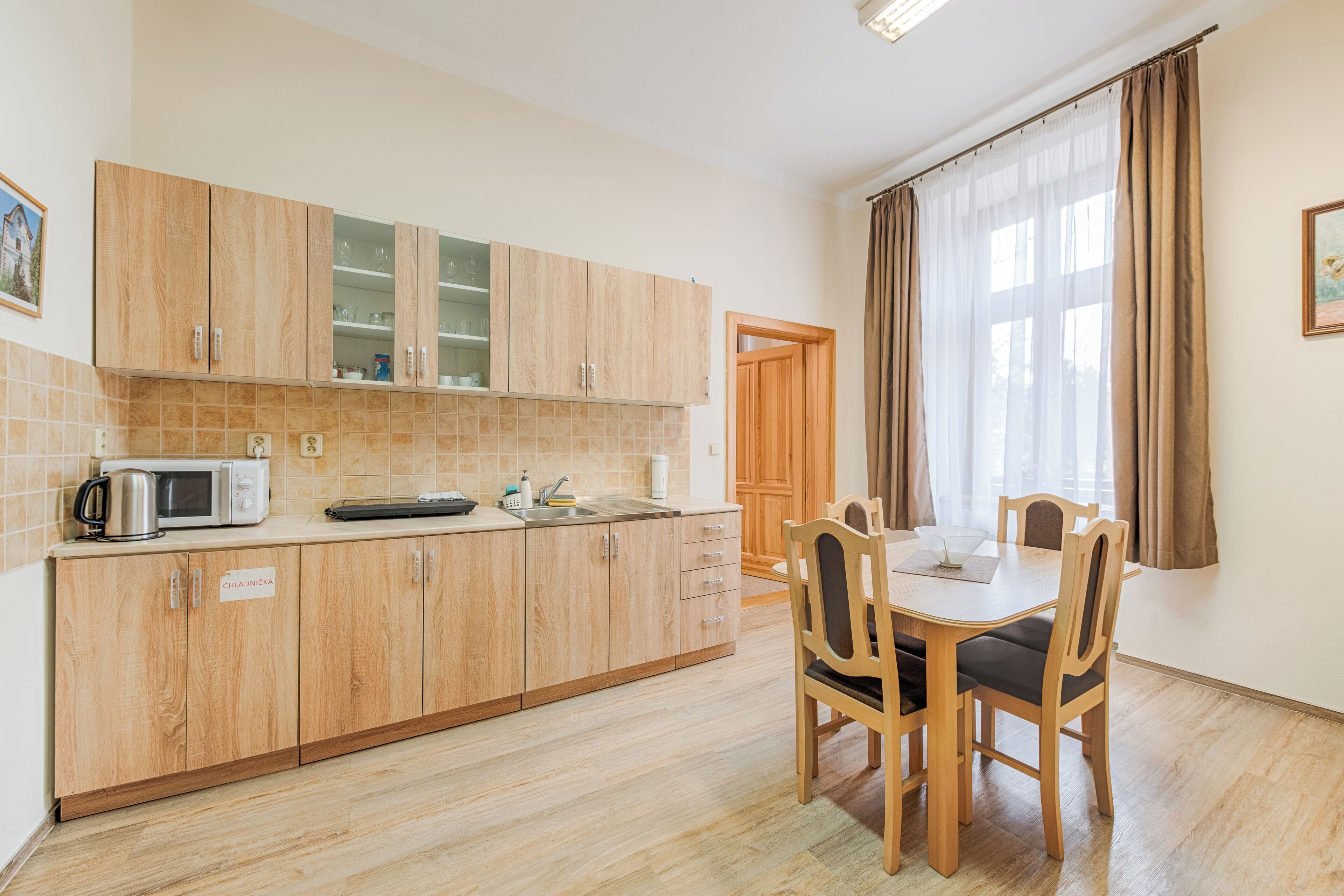 A kitchen with wooden cabinets, a microwave, and a dining table with chairs.