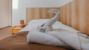 A neatly made bed with a folded towel and a small card on it. - Penzion Vila Machů (Kopřivnice)