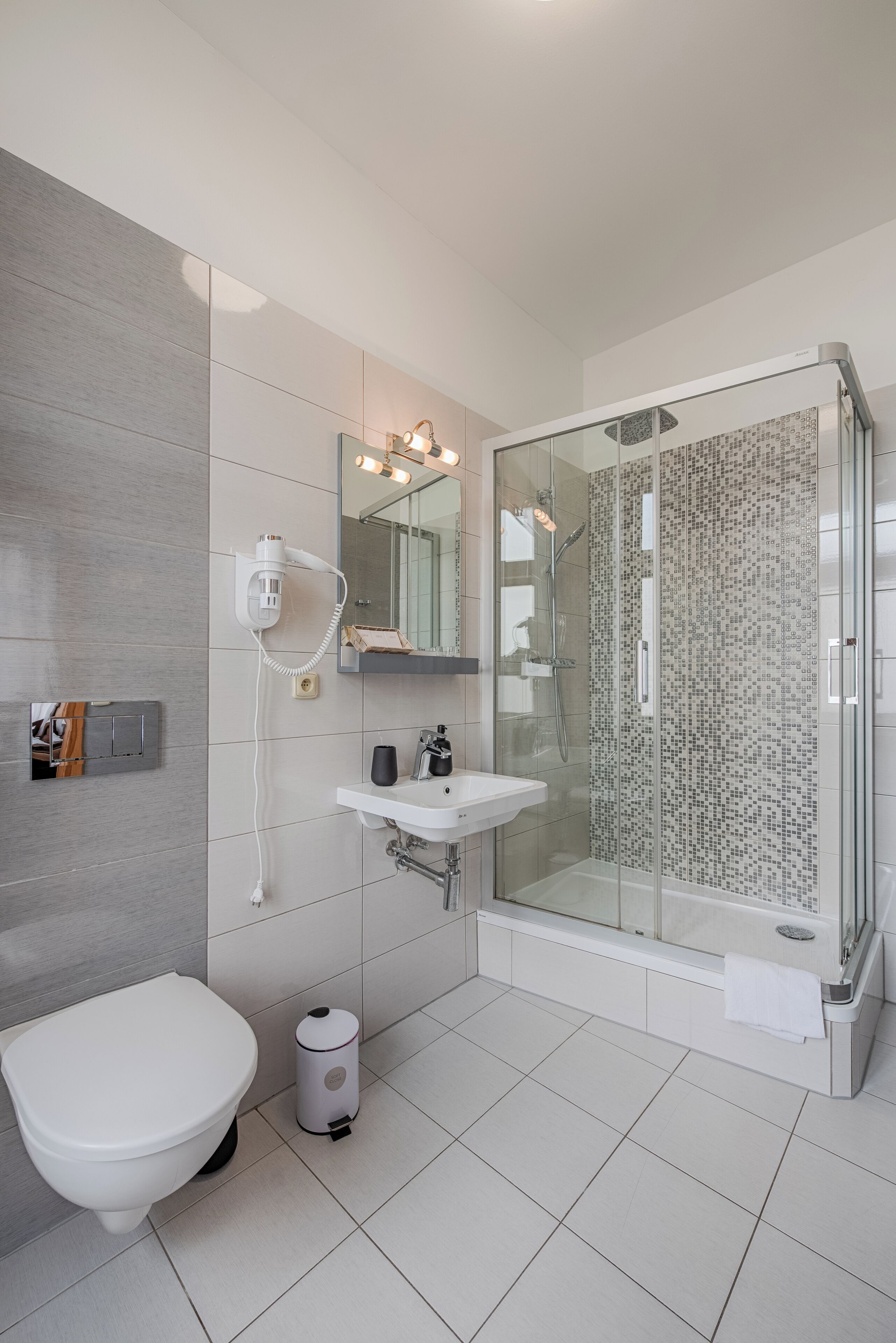 A modern bathroom with a toilet, sink, and glass-enclosed shower.