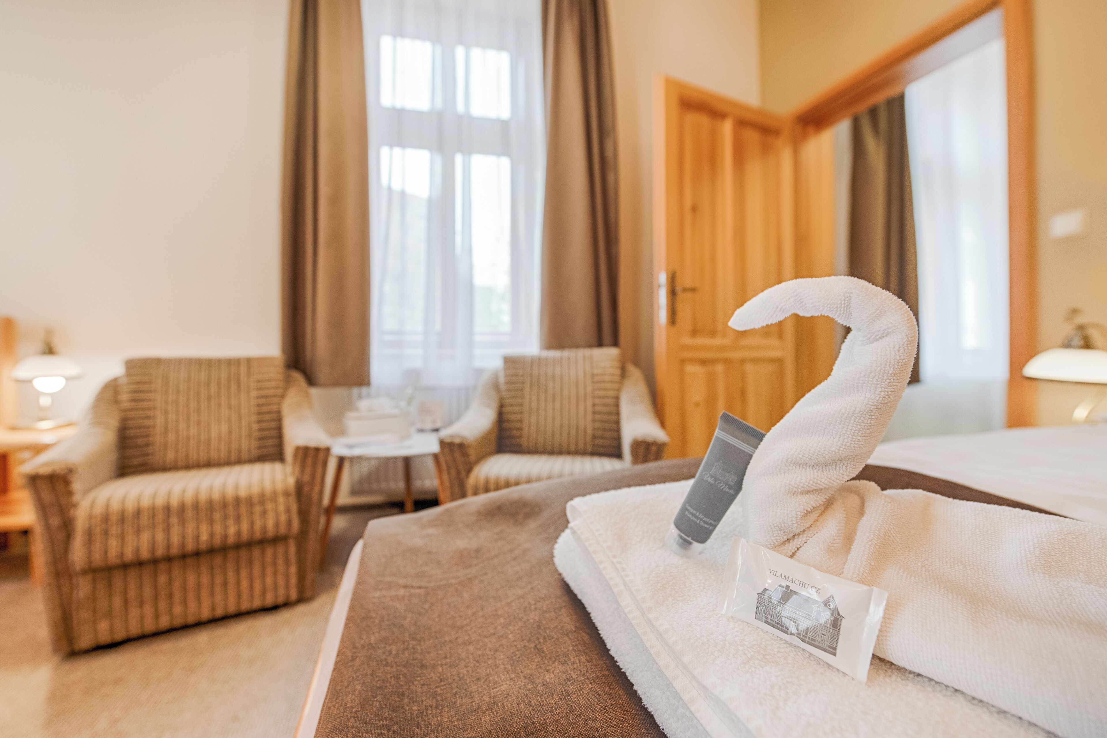 Een hotelkamer met een bed, een stoel, een tafel en een raam met gordijnen.