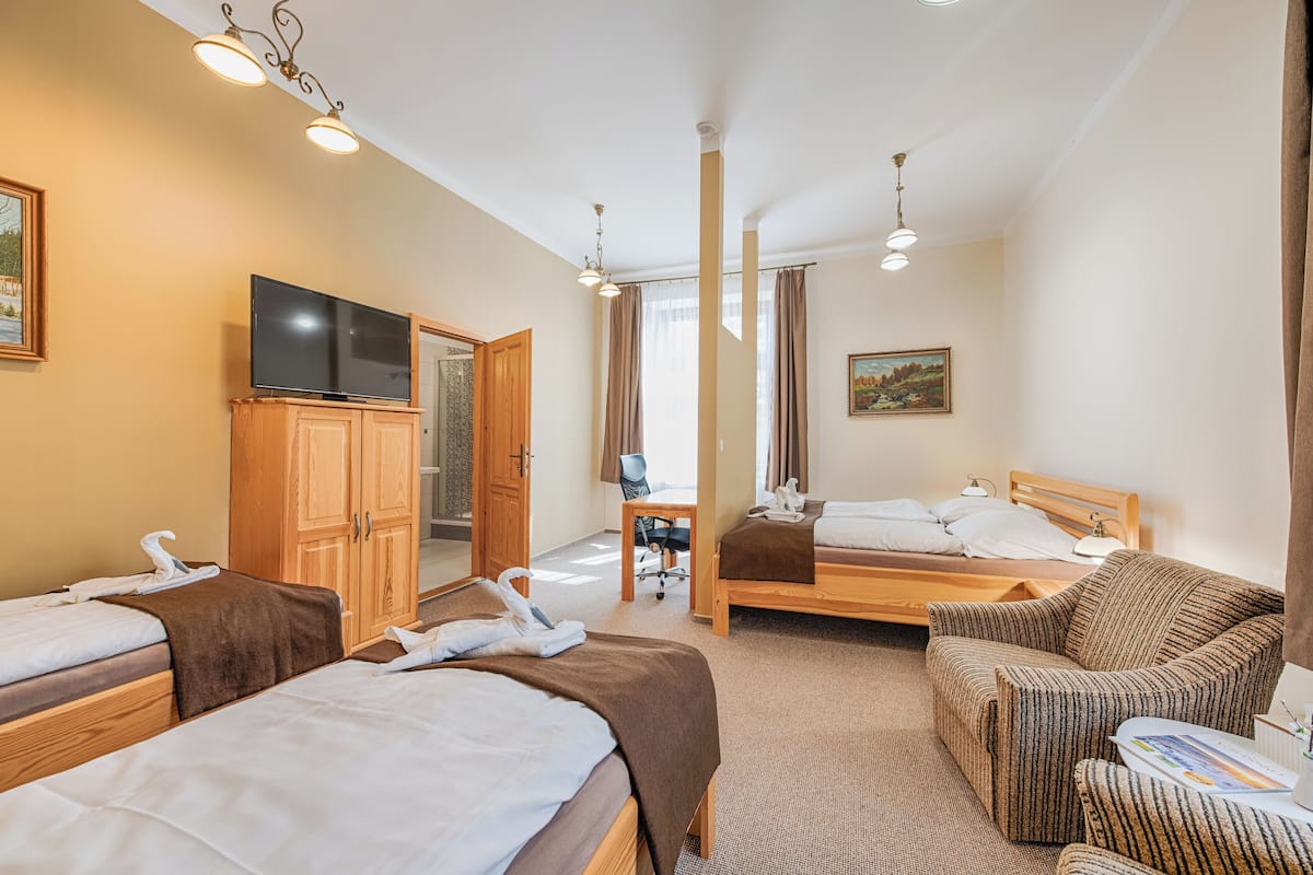 A hotel room with two beds, a TV, wooden furniture, and a desk.