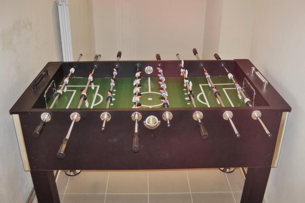Una mesa de futbolín con superficie de juego verde y barras de metal.