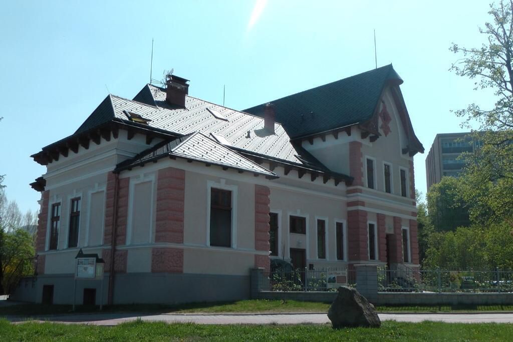 A two-story building with a symmetrical facade, large windows, and a prominent gabled roof.
