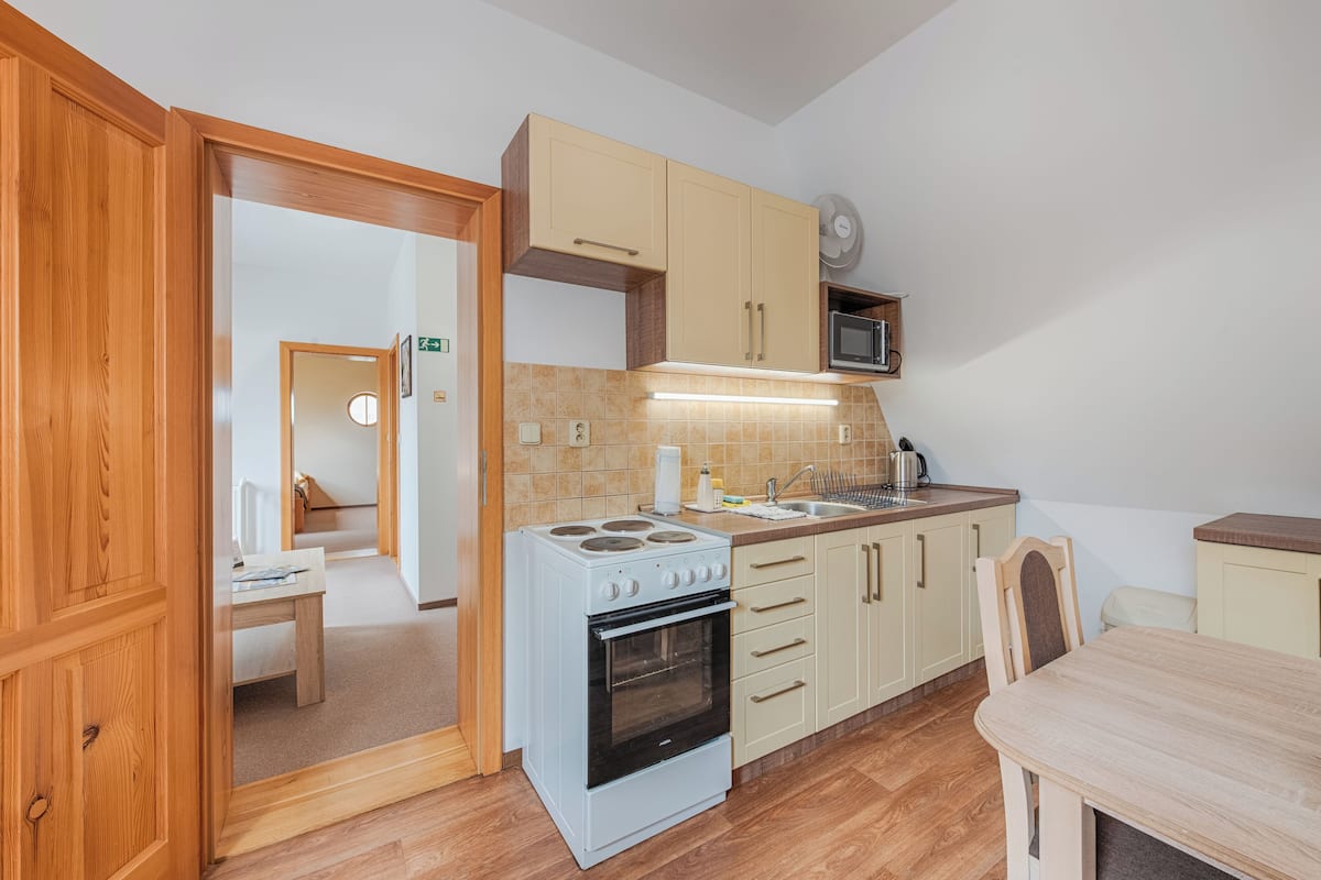 A compact kitchen with a stove, microwave, and wooden cabinets.