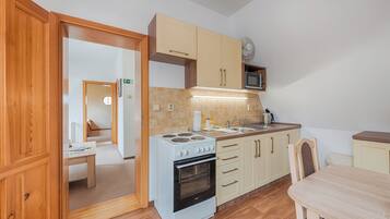 A compact kitchen with a stove, microwave, and wooden cabinets.