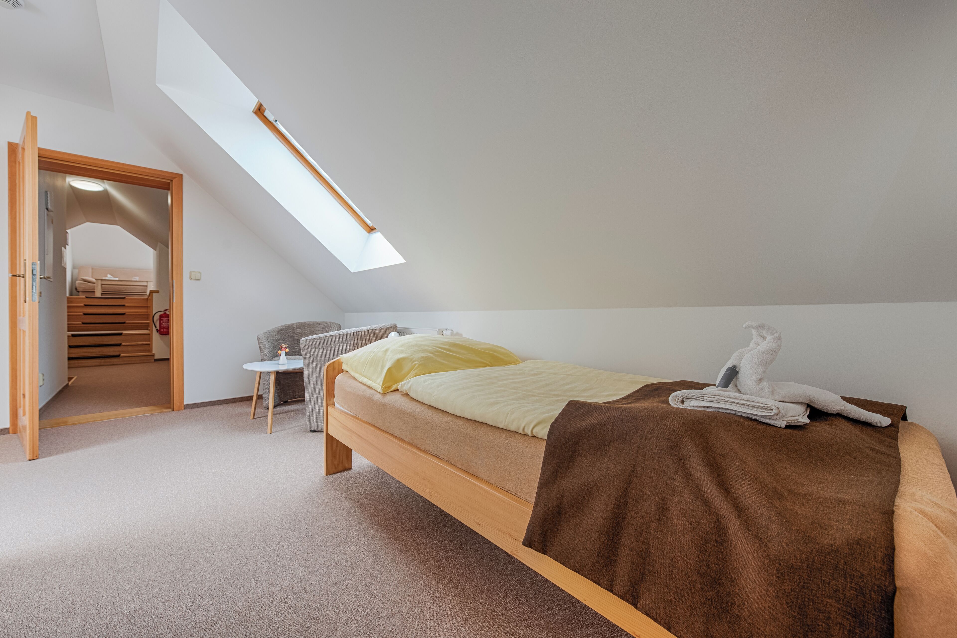 Ein Schlafzimmer mit Oberlicht, einem Bett, einem kleinen Tisch und einem Stuhl.