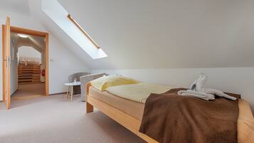 Ein Schlafzimmer mit Oberlicht, einem Bett, einem kleinen Tisch und einem Stuhl.