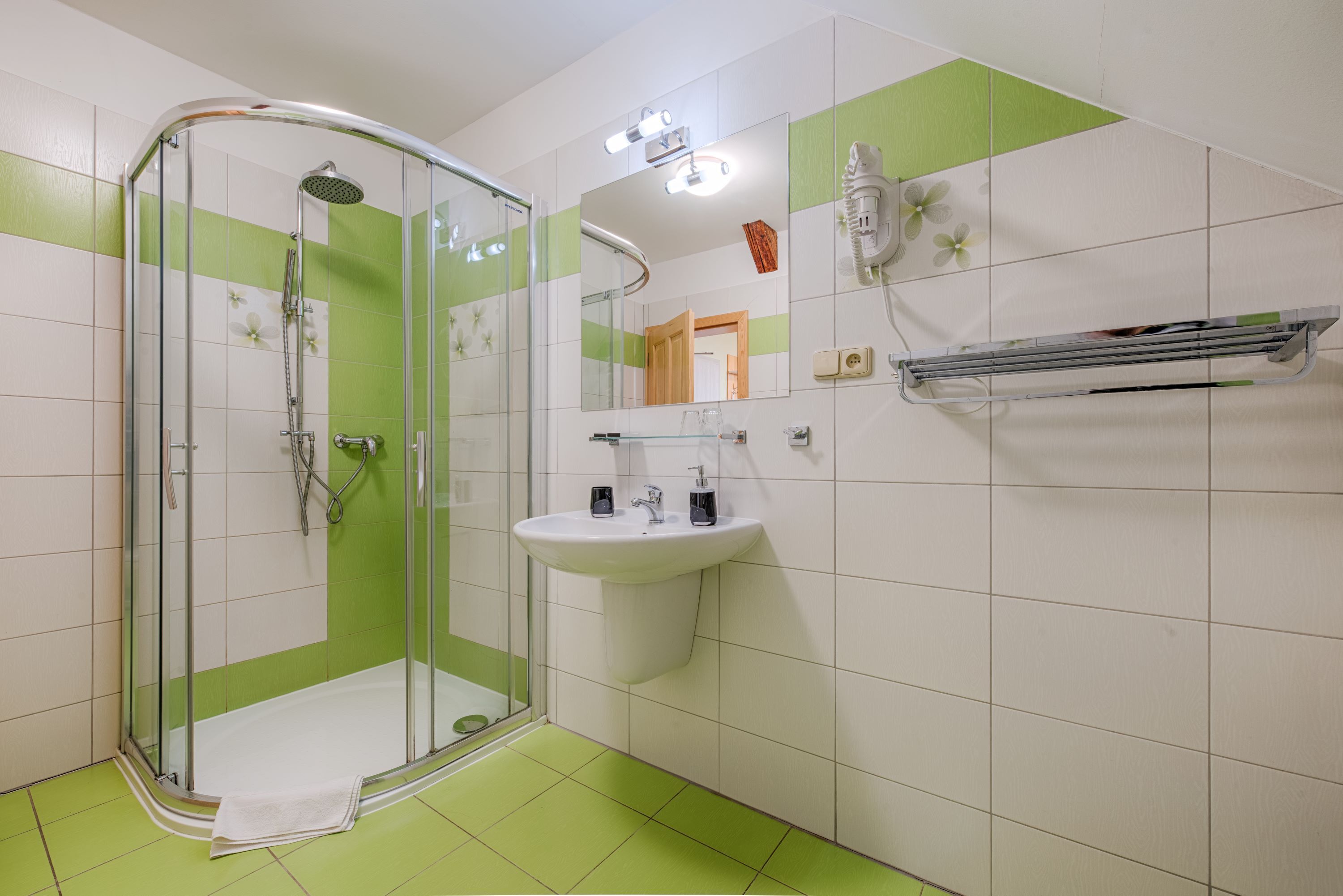 A bathroom with a glass-enclosed shower, a white sink, and a mirror.