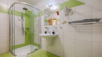 Un baño con ducha de vidrio, un lavabo blanco y un espejo.