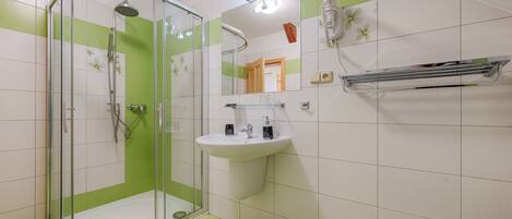 A bathroom with a glass-enclosed shower, a white sink, and a mirror.
