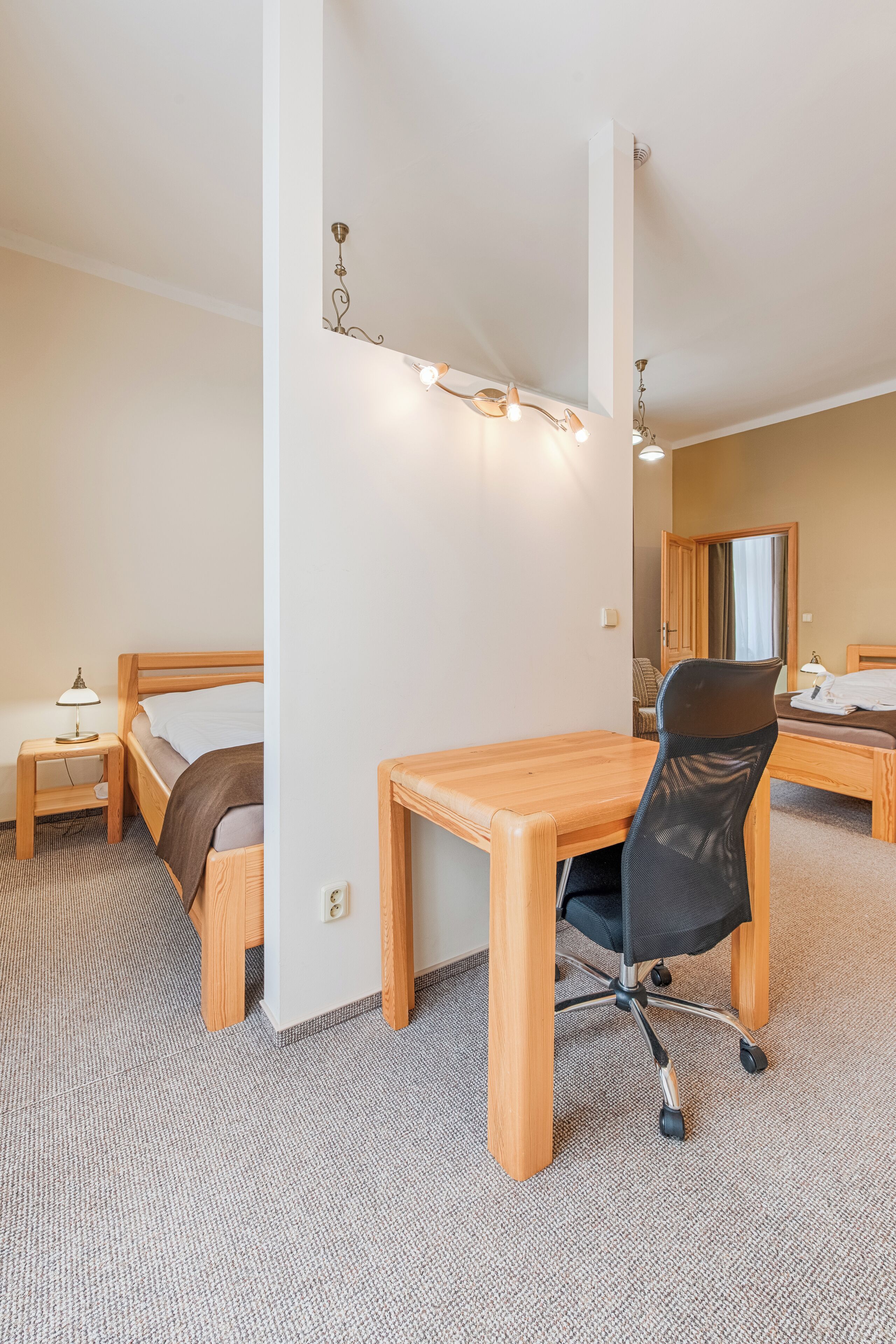 A hotel room with a wooden bed, a desk, a chair, and a small table.