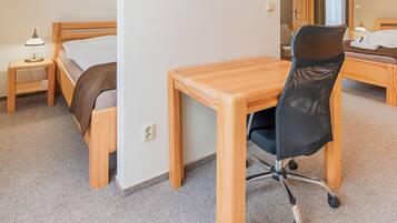 A hotel room with a wooden bed, a desk, a chair, and a small table.