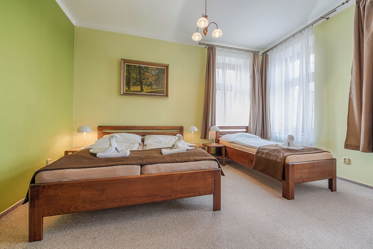 A hotel room with two beds, a painting on the wall, and a chandelier.