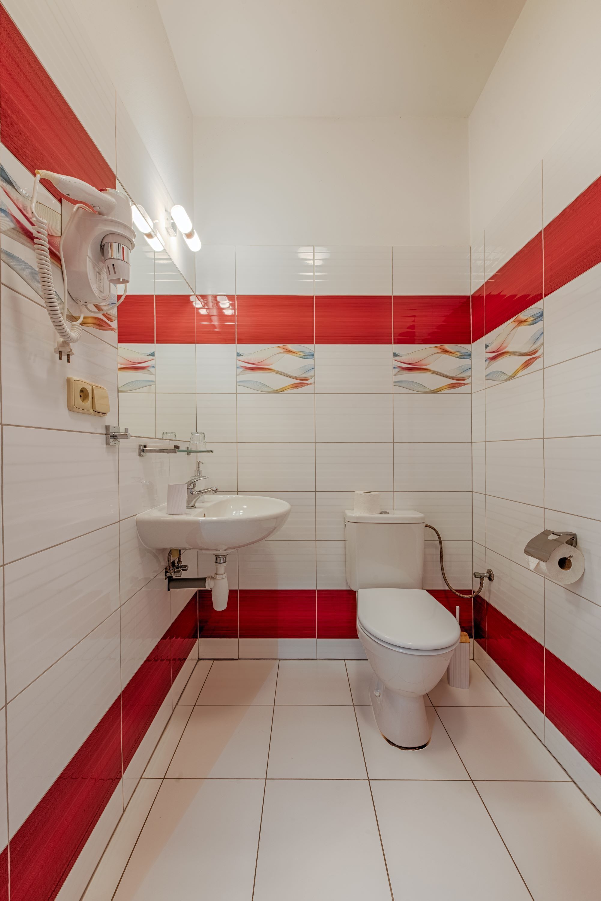 A bathroom with a white sink, toilet, and red-tiled walls.
