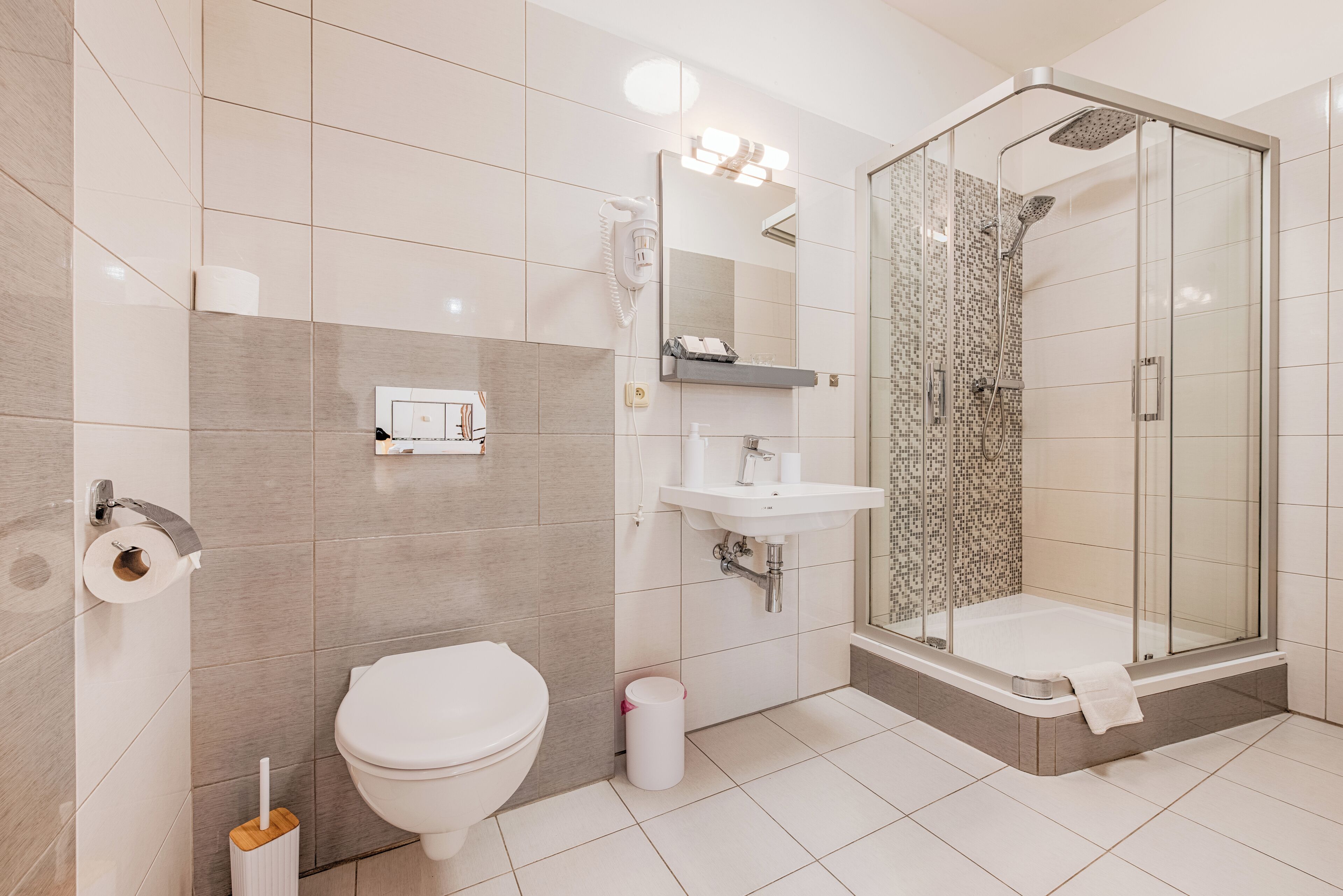 A modern bathroom with a toilet, sink, shower, and a glass-enclosed shower stall.