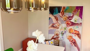 A dining area with a white table, blue vase, green and red chairs, and a painting on the wall. - Luxury old building within walking distance of the city center - Lübeck's best location - water view (Lübeck)