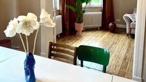 A dining area with a table, chairs, a vase with flowers, a potted plant, and hanging light fixtures. - Luxury old building within walking distance of the city center - Lübeck's best location - water view (Lübeck)