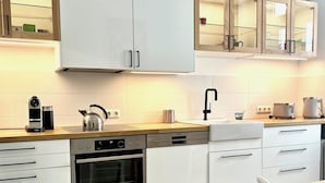 A modern kitchen with white cabinetry, a built-in oven, and a coffee machine. - Luxury old building within walking distance of the city center - Lübeck's best location - water view (Lübeck)