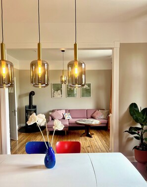 A modern living room with a sofa, a round coffee table, and hanging pendant lights. - Luxury old building within walking distance of the city center - Lübeck's best location - water view (Lübeck)