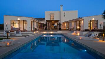 Une maison moderne dotée d’une piscine, d’un espace extérieur aménagé et d’une entrée bien éclairée.
