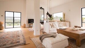 A spacious living room with a large window, a wooden coffee table, and a white sofa.