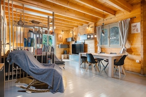 Un interior de madera con zona de comedor, televisor y estantería.