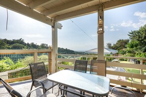 Un espacio de estar al aire libre cubierto con una mesa y sillas, con vistas a un paisaje exuberante.
