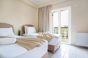 Ein Hotelzimmer mit zwei Betten, einem großen Fenster mit Vorhängen und Blick ins Freie.