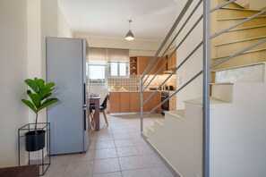 Eine moderne Küche mit Kühlschrank, Essbereich und einer Treppe, die zu einer weiteren Ebene führt.