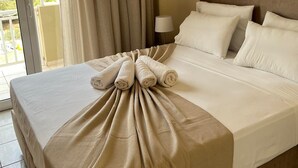A hotel room with a bed, a nightstand, a lamp, and a view through a window. - Apartment 'Solomos' with Sea View, Wi-Fi and Air Conditioning (Elios Proni)