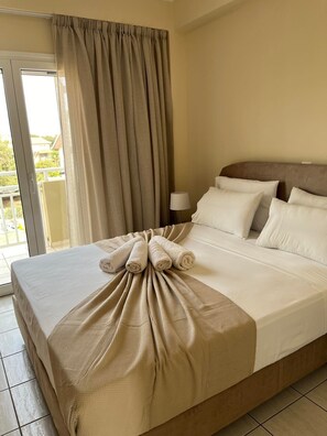 Ein Hotelzimmer mit Bett, Nachttisch, Lampe und Blick durch ein Fenster.