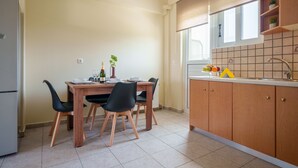 A kitchen with a dining table, chairs, a refrigerator, and a window. - Apartment 'Solomos' with Sea View, Wi-Fi and Air Conditioning (Elios Proni)
