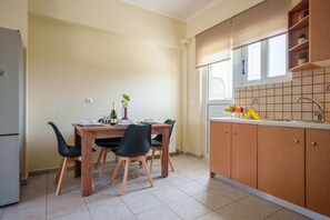 Eine Küche mit Esstisch, Stühlen, einem Kühlschrank und einem Fenster.
