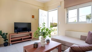 A living room with a TV, sofa, coffee table, and a potted plant. - Apartment 'Solomos' with Sea View, Wi-Fi and Air Conditioning (Elios Proni)