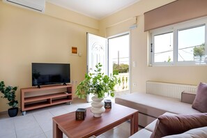 Ein Wohnzimmer mit Fernseher, einer Couch, einem Couchtisch und einem Blumentopf.