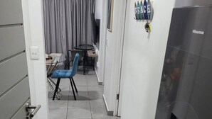 A narrow hallway with a dining area, a TV, and a refrigerator. - Stylish 2BR in Salt Rock - Sheffield Hills (Ballito)