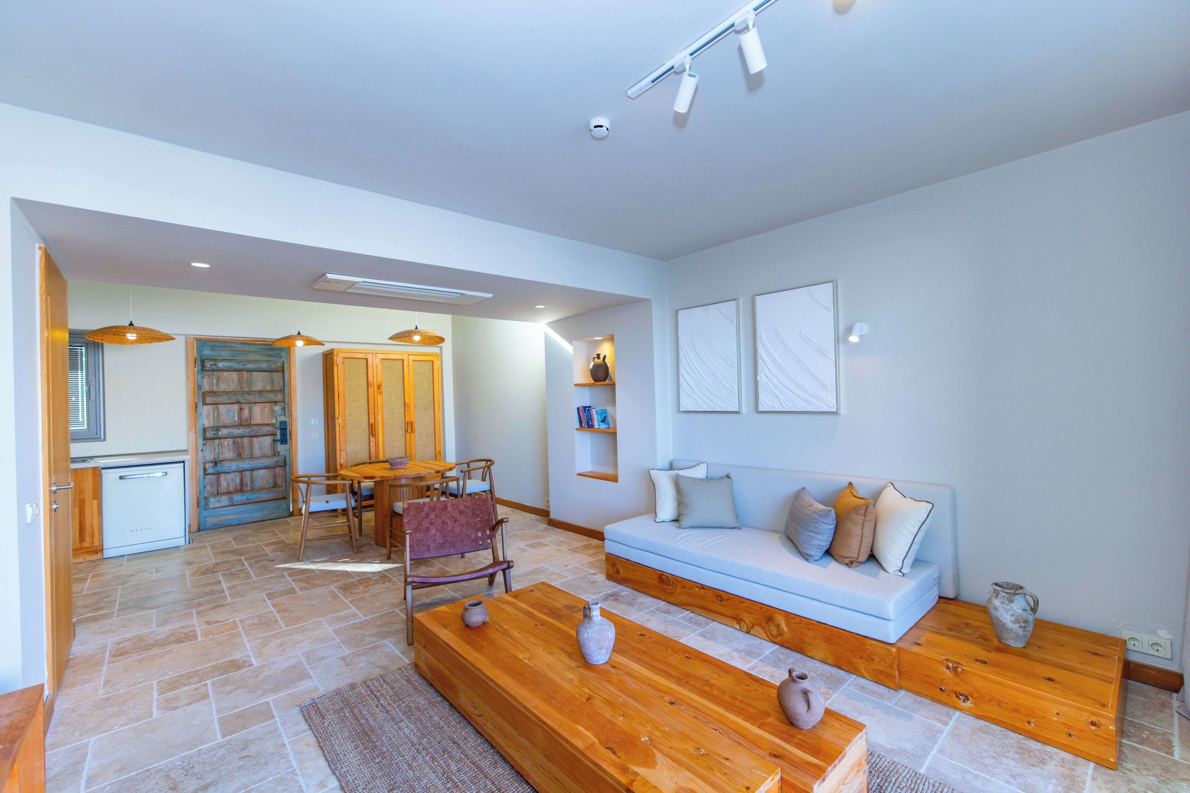 A modern living room with a sofa, coffee table, and a dining area with chairs.