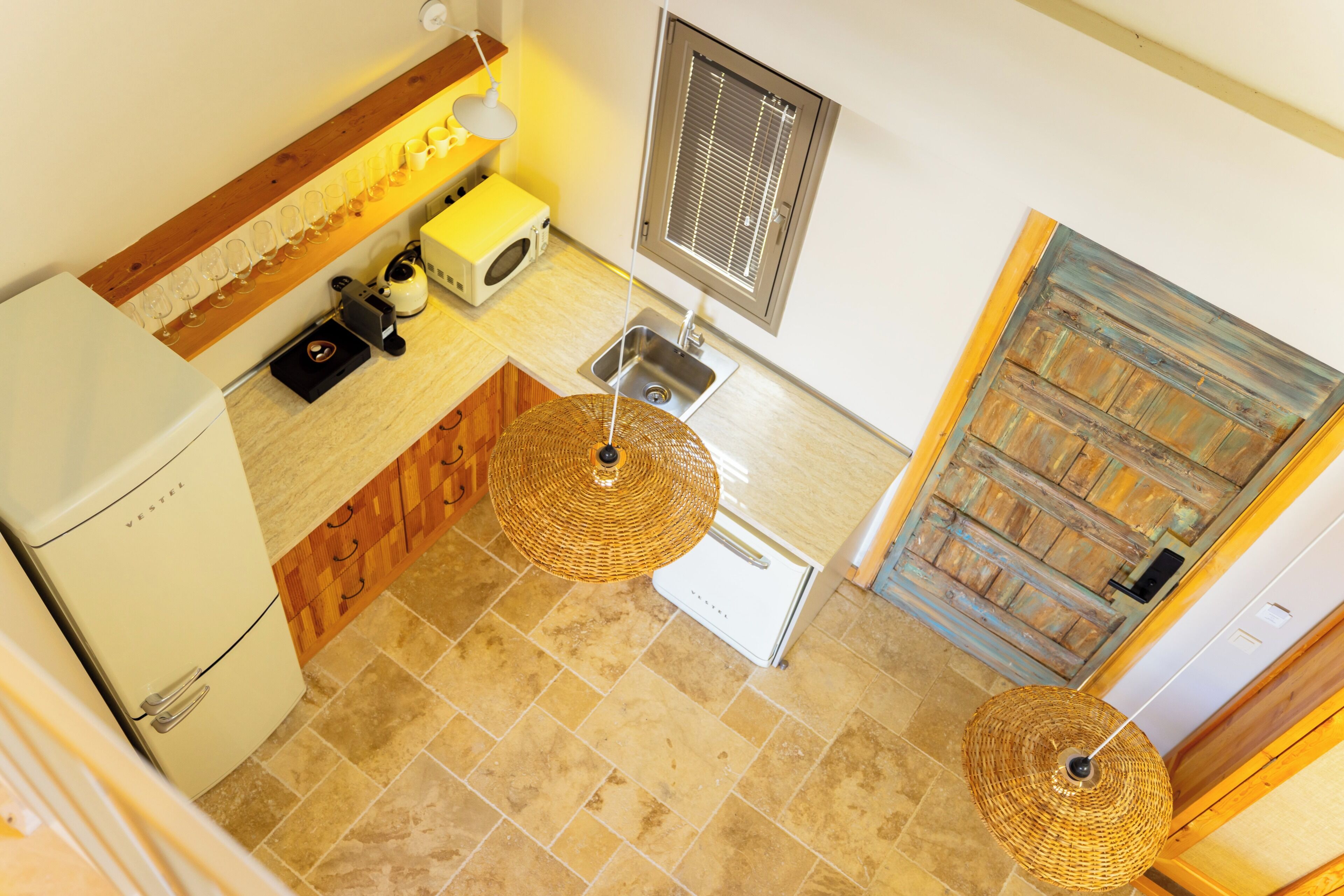 A kitchen with a refrigerator, microwave, sink, and hanging light fixtures.