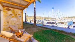 A covered outdoor seating area with stone walls, overlooking a marina with multiple boats.