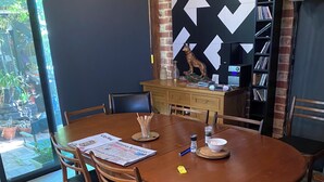 Un coin repas comprenant une table ronde en bois, des chaises, un mur décoratif et une bibliothèque.