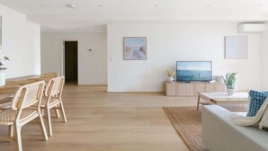 Ein modernes Wohnzimmer mit Essbereich, einem Flachbildfernseher und Kunstwerken an den Wänden.