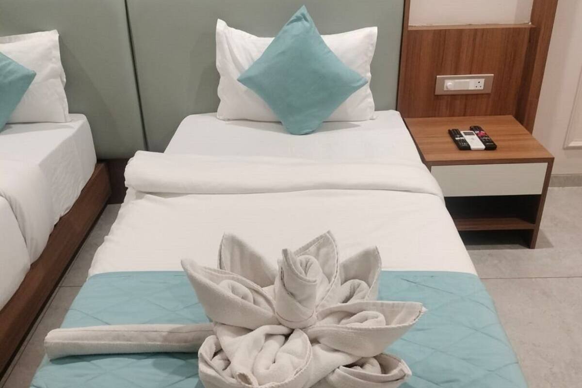 Habitación de hotel con cama, mesita de noche y una presentación de toallas.