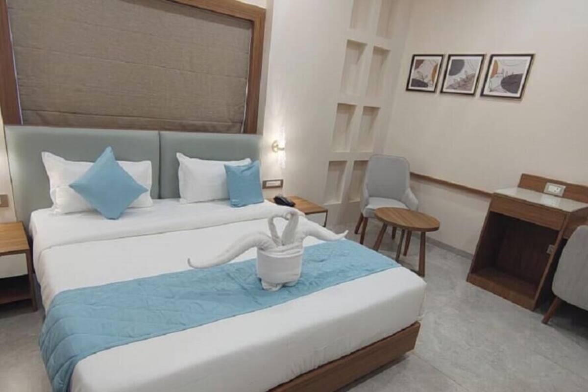 Una habitación de hotel con una cama grande, un escritorio, una silla y una mesita.