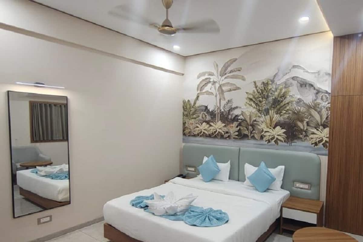 Un dormitorio con cama, mesita de noche, espejo, ventilador de techo y un mural en la pared.