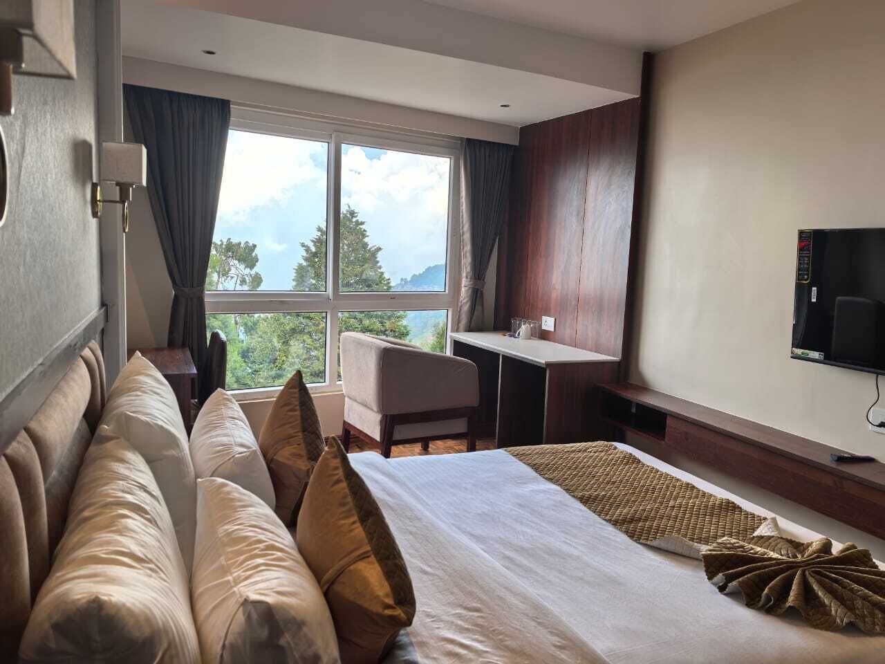 A hotel room with a large bed, a desk, a chair, and a TV.