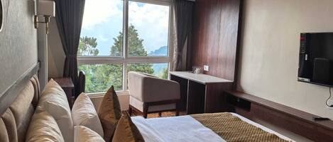 A hotel room with a large bed, a desk, a chair, and a TV.