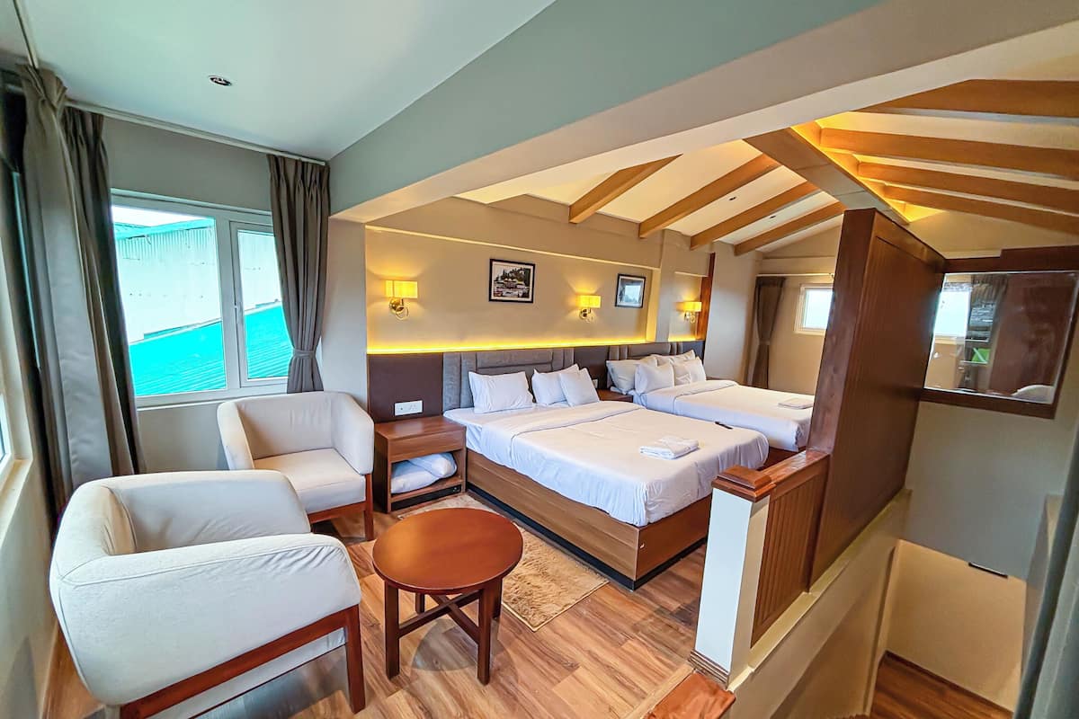 A hotel room with a large bed, two bedside tables, a chair, a small round table, and a mirror.
