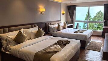 A hotel room with two beds, a desk, and a large window with a view.