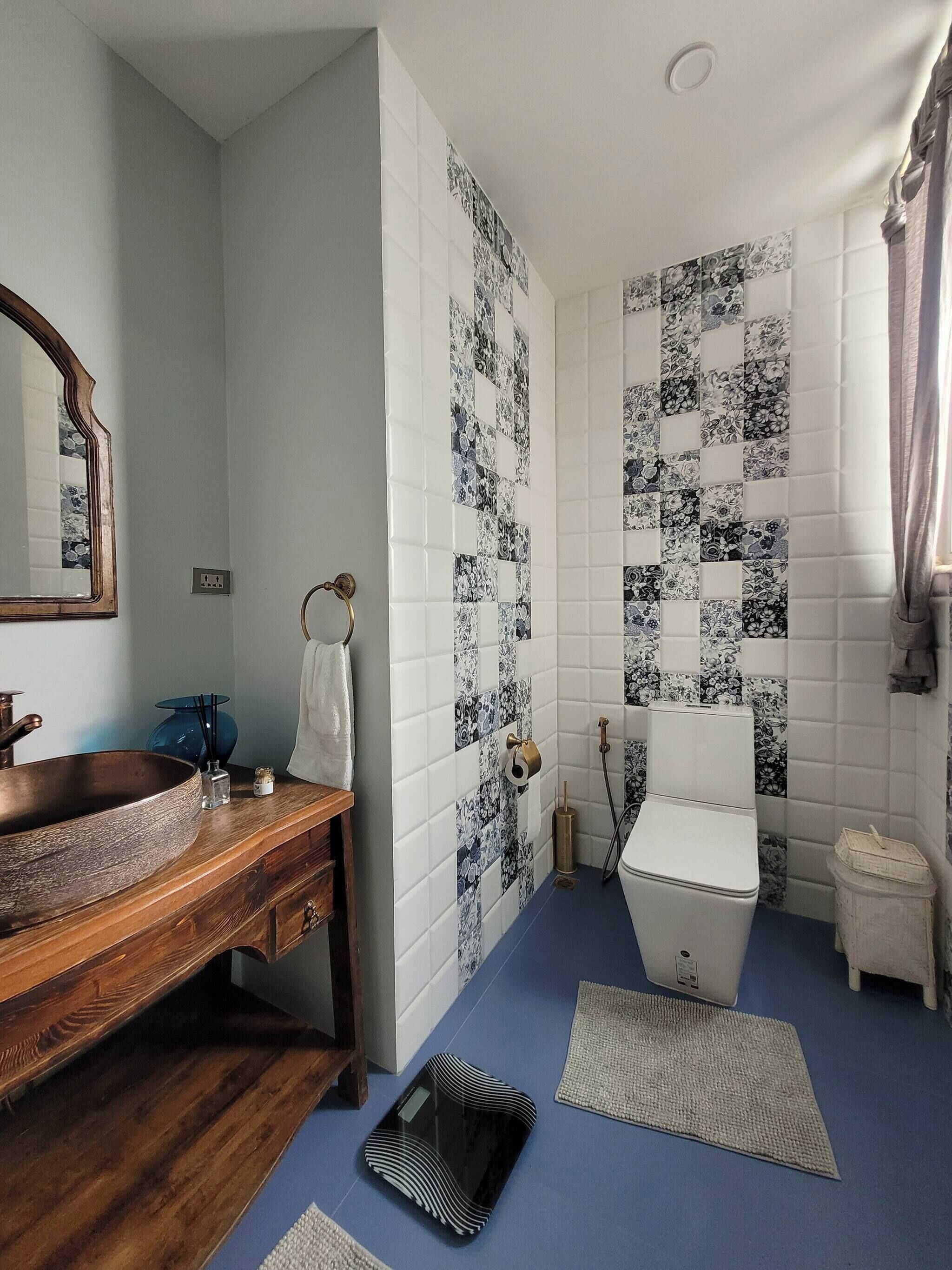 Un baño con tocador de madera, un espejo grande, un inodoro y baldosas estampadas.